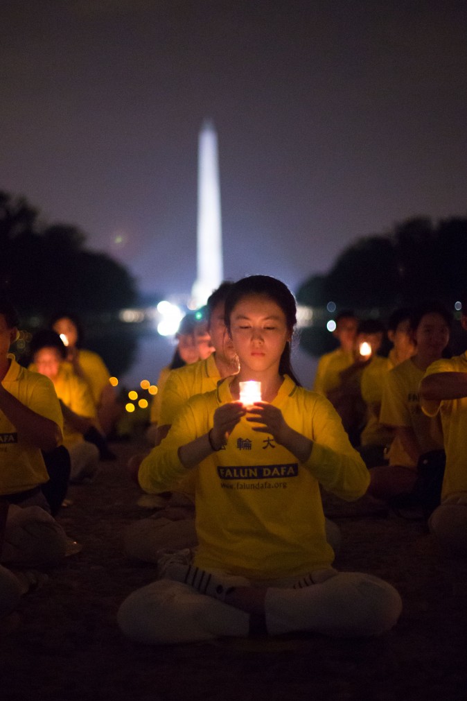 A woman joins Falun Gong practitioners hold a candlelight vigil at the Lincoln Memorial in Washington on July 20, 2017, to honor those who have died during the persecution in China that the Chinese regime started on July 20, 1999. (Benjamin Chasteen/The Epoch Times)