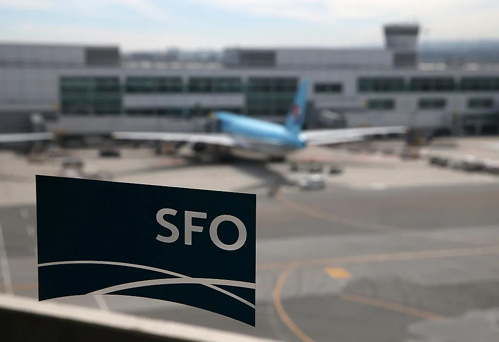 A plane parked at the international terminal is seen through the window of a sky train station at San Francisco International Airport. (Photo by Justin Sullivan/Getty Images)