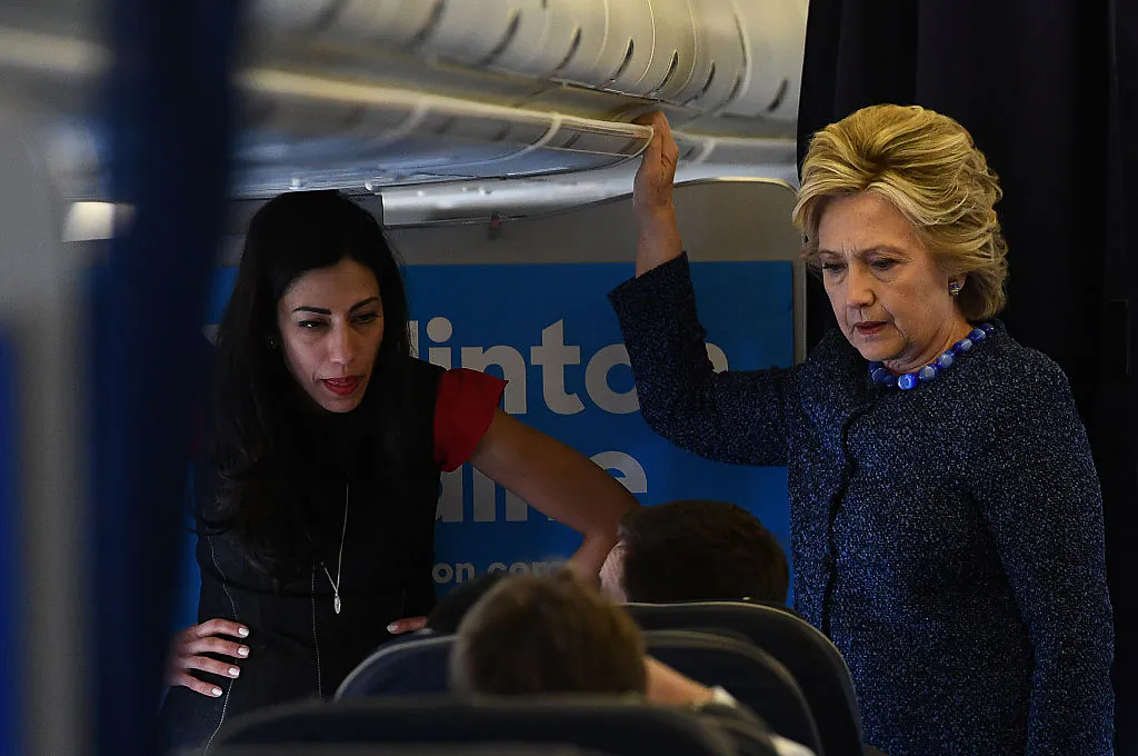 US Democratic presidential nominee Hillary Clinton talks to staff as aide Huma Abedin (L) listens onboard their campaign plane at the Westchester County Airport in White Plains, New York, on October 28, 2016. (JEWEL SAMAD/AFP/Getty Images)