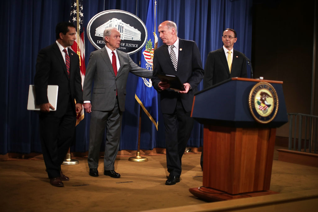 U.S. Attorney General Jeff Sessions (2nd L) and Director of National Intelligence Dan Coats (3rd L) share a moment as Deputy Attorney General Rod Rosenstein (R) and National Counterintelligence and Security Center Director William Evanina (L) look on during an event at the Justice Department August 4, 2017 in Washington, DC. Sessions held the event to discuss "leaks of classified material threatening national security." (Photo by Alex Wong/Getty Images)