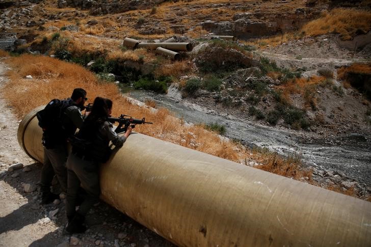 Israeli border police officers guard as sewage flows in the Kidron Valley, on the outskirts of Jerusalem July 6, 2017. (REUTERS/Ronen Zvulun)