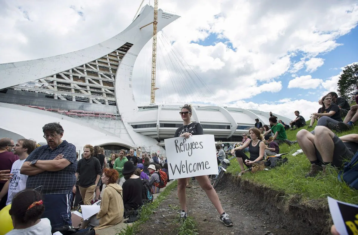 People gather in support of asylum seekers who crossed the border irregularly during a rally outside the Olympic Stadium in Montreal on Aug. 6, 2017. (The Canadian Press/Graham Hughes)