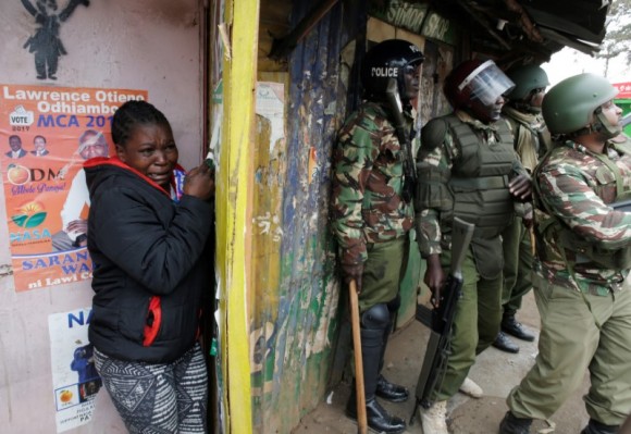 A woman cries as she stand behind policemen during clashes between supporter of opposition leader Raila Odinga and policemen in Kibera slum in Nairobi, Kenya, August 12, 2017. (Reuters/Goran Tomasevic)