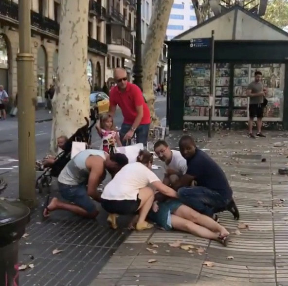 People help an injured woman lying on the ground after a van crashed into pedestrians near the Las Ramblas avenue in central Barcelona, Spain August 17, 2017, in this still image from a video obtained from social media. Courtesy of Carlos Tena Gallardo/via REUTERS