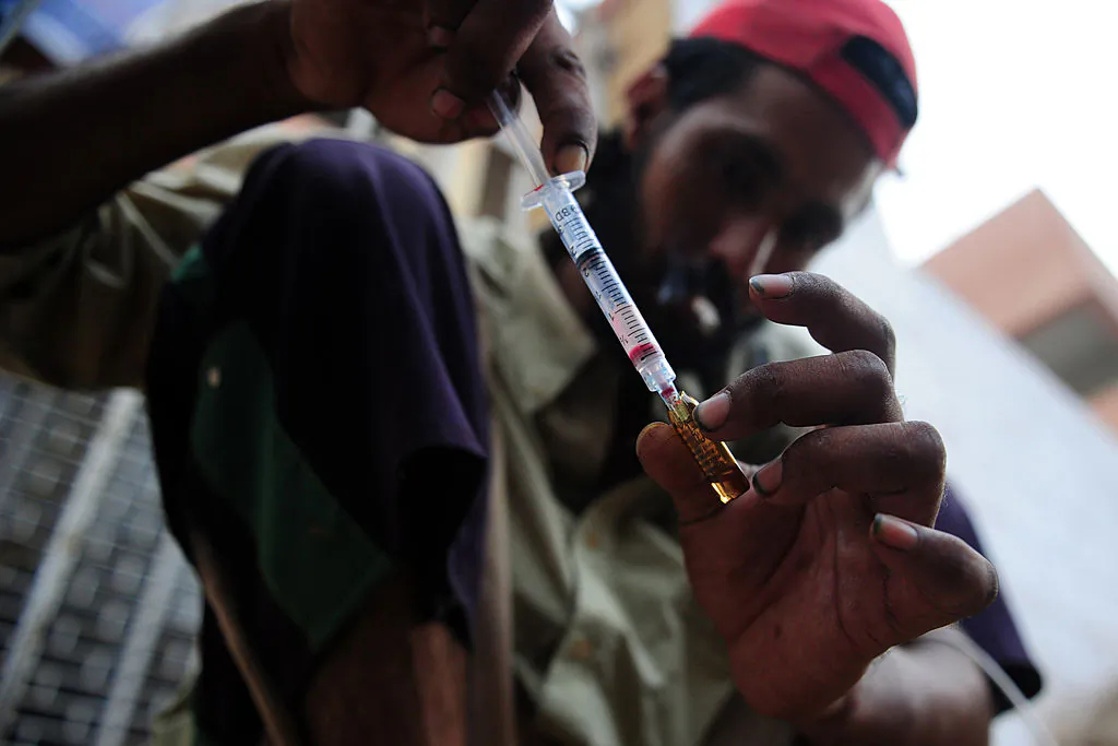 A drug user prepares a syringe of drugs (ASIF HASSAN/AFP/GettyImages)