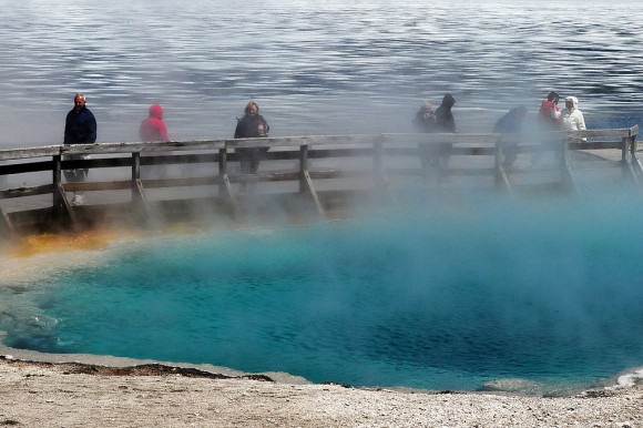 Tourists walk beside a hot spring and the partially frozen Yellowstone Lake at the West Thumb Geyser Basin in the Yellowstone National Park, Wyoming on June 2, 2011. (MARK RALSTON/AFP/Getty Images)