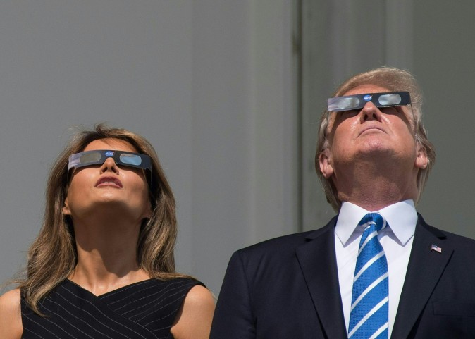US President Donald Trump and First Lady Melania Trump look up at the partial solar eclipse from the balcony of the White House in Washington, DC, on August 21, 2017. The Great American Eclipse completed its journey across the United States Monday, with the path of totality stretching coast-to-coast for the first time in nearly a century. / AFP PHOTO / NICHOLAS KAMM        (Photo credit should read NICHOLAS KAMM/AFP/Getty Images)