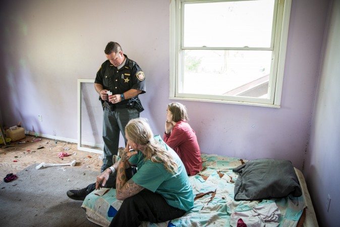 Montgomery County Deputy Sheriff Andy Teague, speaks with two people who had allegedly been using drugs inside an abandoned home in the Drexel neighborhood of Dayton, Ohio, on Aug. 3, 2017. (Benjamin Chasteen/The Epoch Times)
