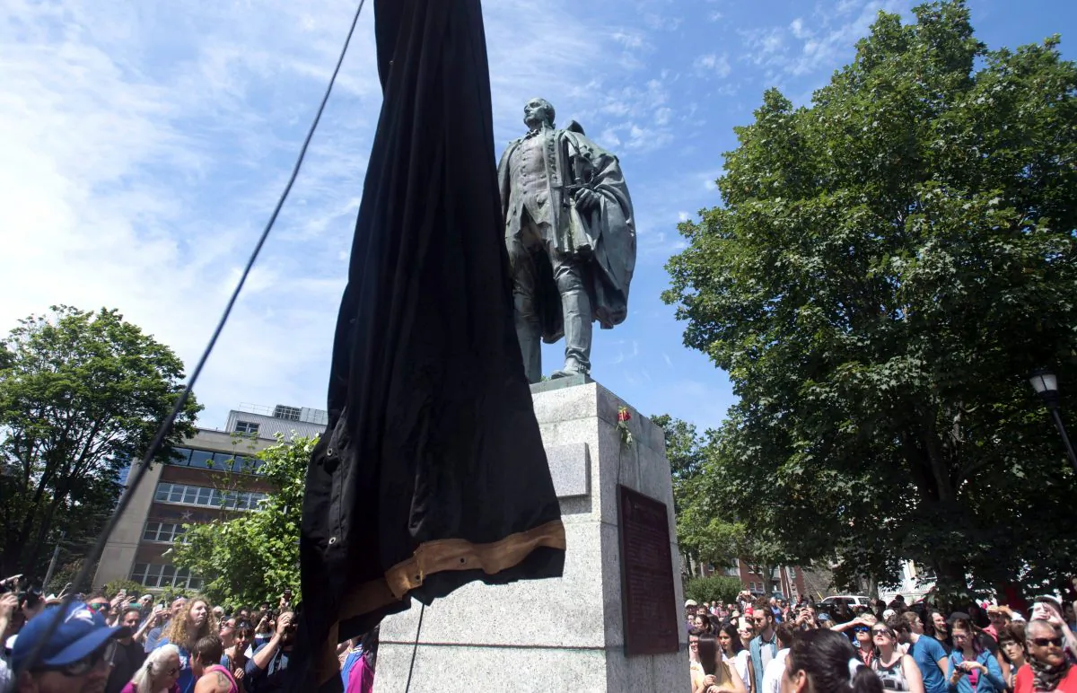 A statue of Edward Cornwallis is about to be covered as activists protest in Cornwallis Park in Halifax on July 15, 2017. The protesters, who had pledged to topple the statue of Halifax's founder, claimed victory after it was covered in a tarp. (THE CANADIAN PRESS/Darren Calabrese)