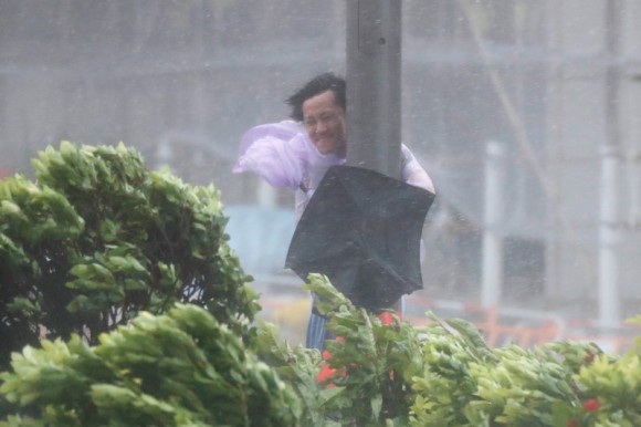 A man holds onto a lamp post against strong wind as Typhoon Hato hits Hong Kong, China August 23, 2017. (Reuters/Tyrone Siu)