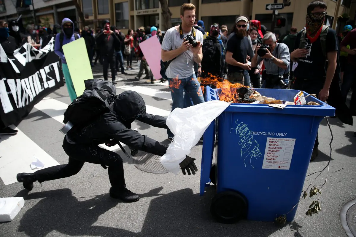 An Antifa extremist pushes a burning recycling bin at Trump supporters during a free speech rally in Berkeley, Calif., on April 15, 2017. (Elijah Nouvelage/Getty Images)
