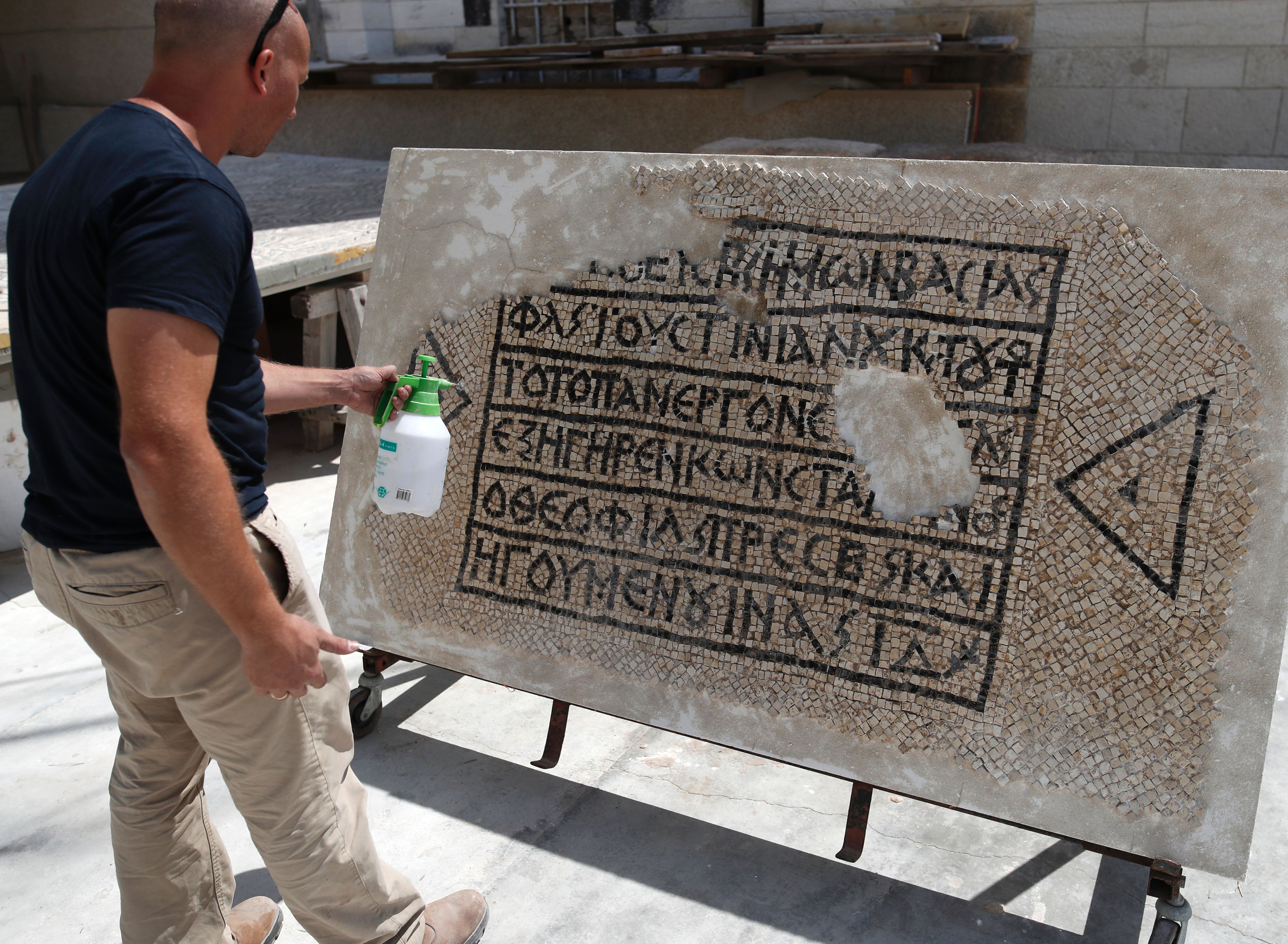 An archaeologist works on part of a 1,500-year-old mosaic floor bearing the names of Byzantine Emperor Justinian, at the Rockefeller Museum in Jerusalem, on August 23, 2017, after they unearth a portion of ancient mosaic near the city's Damascus Gate. (AHMAD GHARABLI/AFP/Getty Images)