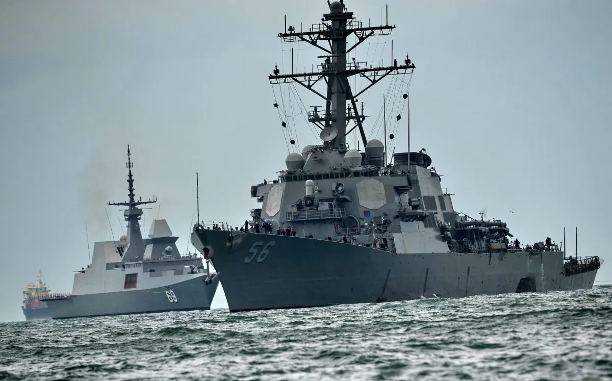 The guided-missile destroyer USS John S. McCain (R), with a hole on its portside after a collision with an oil tanker, is escorted by Singapore Navy RSS Intrepid (L) to Changi naval base in Singapore on August 21, 2017. Ten US sailors were missing and five injured after their destroyer collided with a tanker east of Singapore on Aug. 20, the second accident involving an American warship in two months. (ROSLAN RAHMAN/AFP/Getty Images)
