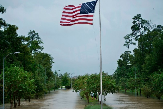 People walk along a flooded road's median during the aftermath of Hurricane Harvey on August 29, 2017 in Houston, Texas. (BRENDAN SMIALOWSKI/AFP/Getty Images)