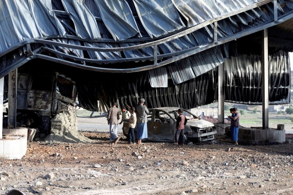 People look at a burnt car at a petrol station near a checkpoint of the armed Houthi movement hit by a Saudi-led air strike near Sanaa, Yemen August 30, 2017. (Reuters/Khaled Abdullah)