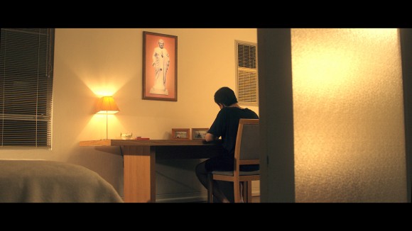 Caption: Eric Jia in a scene from the short film "Split by the State", writing to Australia's Prime Minister seeking urgent help to save his father. (Alexander Nilsen)
