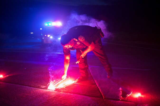A police officer lays down a safety flare while blocking the road leading to the Arkema SA plant which was hit by floods caused Tropical Storm Harvey near Crosby, Texas on Aug. 31, 2017. (REUTERS/Adrees Latif)