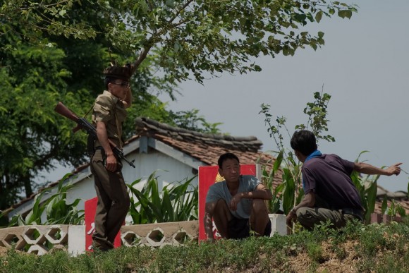 A North Korean soldier speaks with North Korean farmers as they stand on the banks of the Yalu river near Sinuiju, opposite the Chinese border city of Dandong on July 5, 2017. (NICOLAS ASFOURI/AFP/Getty Images)