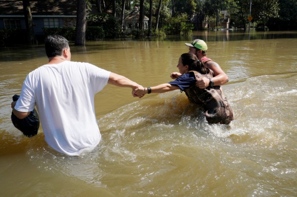 Melissa Ramirez (C) struggles against the current flowing down a flooded street helped by Edward Ramirez (L) and Cody Collinsworth as she tried to return to her home for the first time since Harvey floodwaters arrived in Houston, Texas, U.S. September 1, 2017. (REUTERS/Rick Wilking)