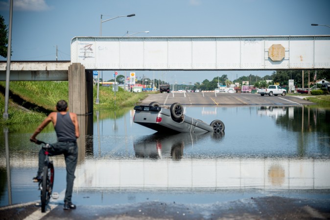 A bicyclist stops to look at a truck flipped into floodwater in Port Arthur in Houston on on Sept. 1. Houston was limping back to life on Friday one week after Hurricane Harvey slammed into America's fourth-largest city and left a trail of devastation across other parts of southeast Texas. (Emily Kask /AFP/Getty Images)