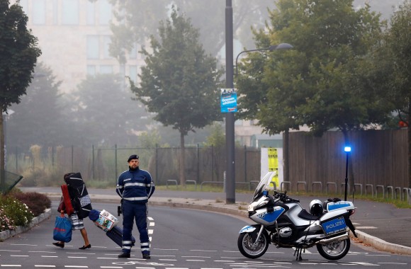 A woman carries her belongings walking past a police officer as some 60,000 people in Germany's financial capital are about to evacuate the city while experts defuse an unexploded British World War Two bomb found during renovations on the university's campus in Frankfurt, Germany, September 3, 2017. (Reuters/Kai Pfaffenbach)