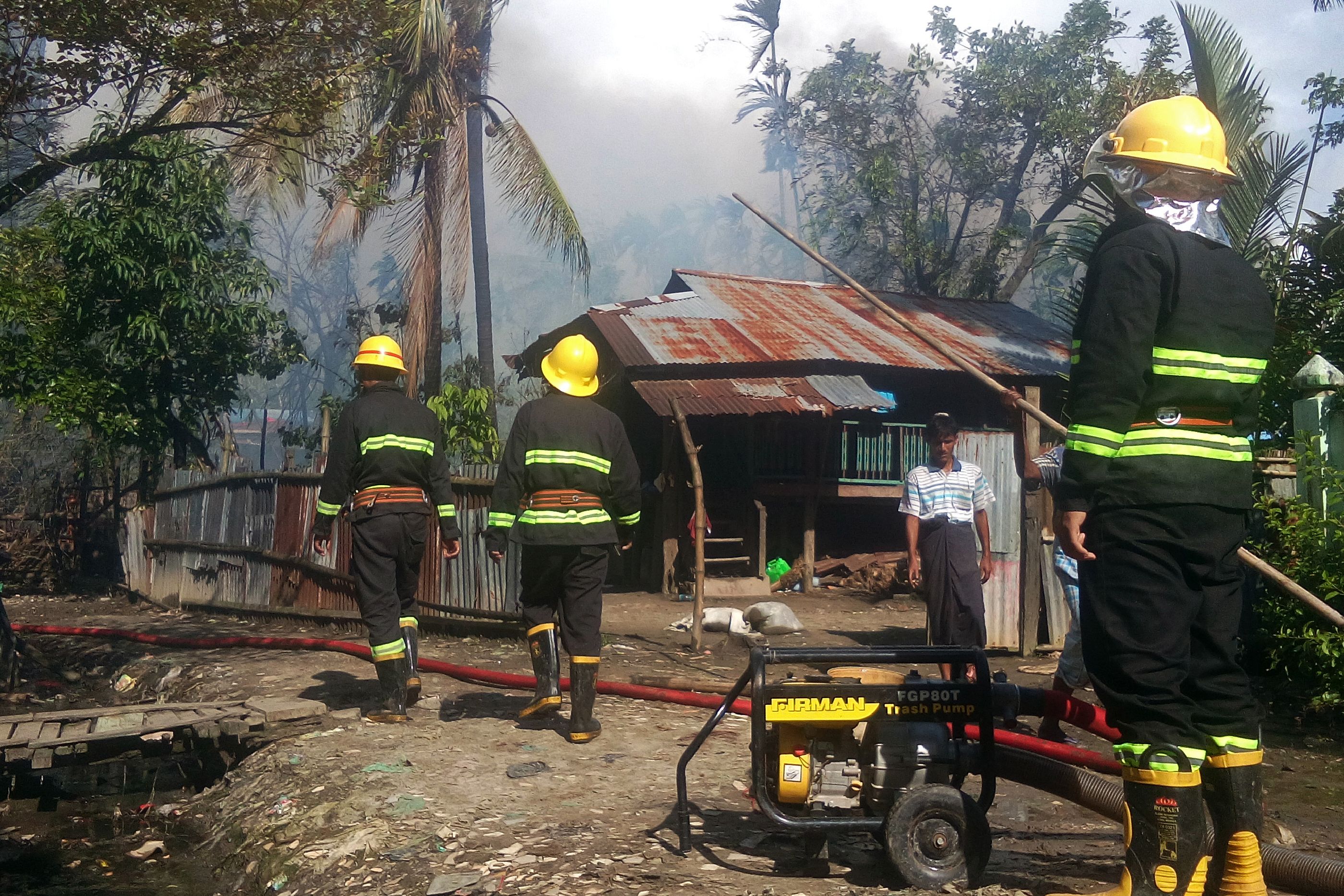 This picture taken on August 27, 2017 shows firefighters attempting to extinguish fires from houses burnt by Rohingya militants at the Maungdaw township in Rakhine State in Myanmar. Myanmar's Aung San Suu Kyi on August 28 accused Rohingya fighters of burning down homes and using child soldiers during a recent surge in violence in troubled Rakhine state, allegations denied by the militants themselves. / AFP PHOTO / STR (Photo credit should read STR/AFP/Getty Images)