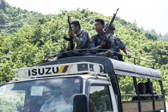 Myanmar police sit on the roof of a truck as they provide protection for staff from the United Nations (UN) and International Non-Governmental Organizations (INGOs) after a visit to a conflict area, at a check point near the entrance of Maungdaw township in Myanmar's Rakhine State on August 28, 2017. Rohingya Muslims are once more fleeing in droves towards Bangladesh, trying to escape the latest surge in violence in Rakhine state between a shadowy militant group and Myanmar's military. / AFP PHOTO / STR (Photo credit should read STR/AFP/Getty Images)