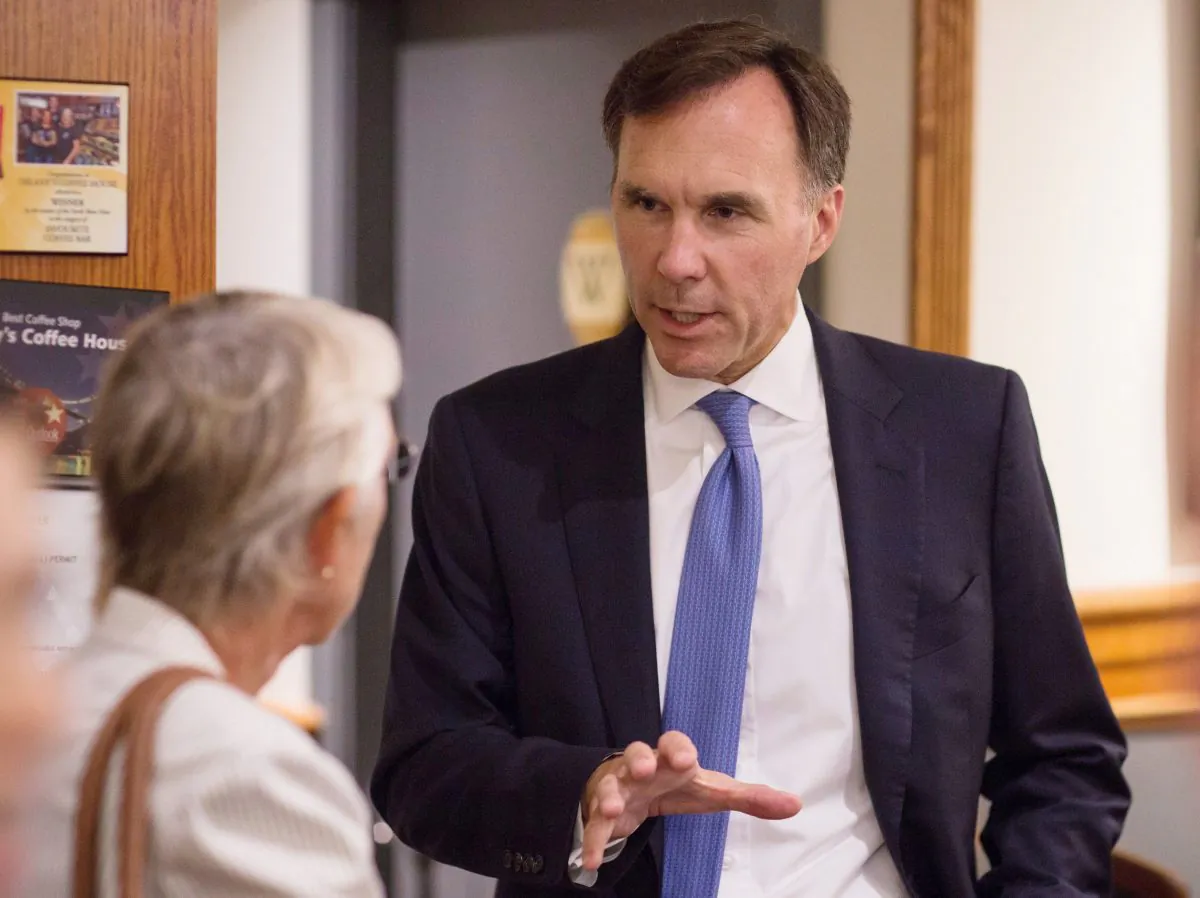 Finance Minister Bill Morneau speaks with a small business owner at a coffee shop in Vancouver on Sept. 5, 2017, before a press conference on controversial income tax reforms for small businesses. (The Canadian Press/Ben Nelms)