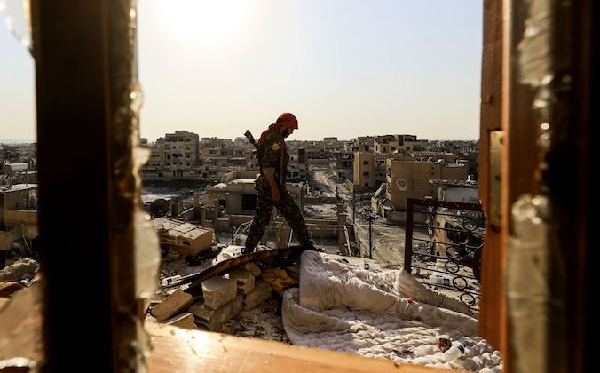 A member of the Syrian Democratic Forces (SDF), a US backed Kurdish-Arab alliance, walks on the roof of a building in the western al-Daraiya neighbourhood of the embattled northern Syrian city of Raqa on September 5, 2017, as they battle to retake the city from ISIS. (DELIL SOULEIMAN/AFP/Getty Images)