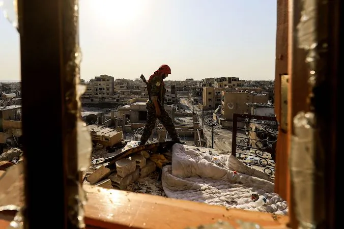 A member of the Syrian Democratic Forces (SDF), a US backed Kurdish-Arab alliance, walks on the roof of a building in the western al-Daraiya neighbourhood of the embattled northern Syrian city of Raqa on September 5, 2017, as they battle to retake the city from ISIS. (DELIL SOULEIMAN/AFP/Getty Images)