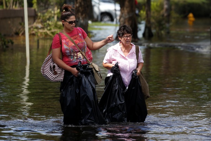 Women walk with garbage bags for waders on a flooded street following Hurricane Irma in North Miami, Florida, on Sept. 11, 2017. (Reuters/Carlo Allegri)