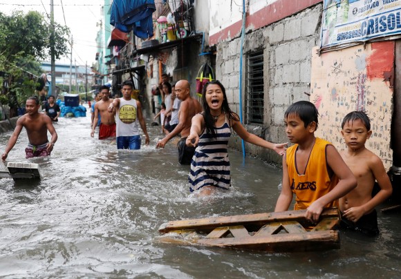 Residents wade in floodwaters in Quezon City, Metro Manila as a storm sweeps across the main Luzon island, Philippines, September 12, 2017. (Reuters/Dondi Tawatao)
