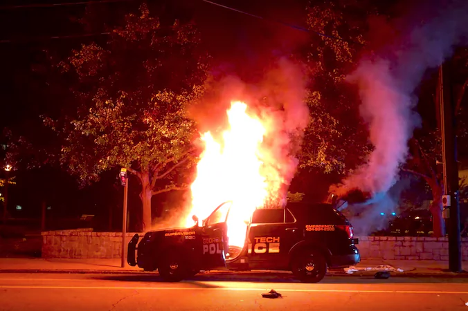 Protesters burn a police car at Georgia Tech on Monday in the wake of the death of student Scout Schultz, who was shot by police when he repeatedly approached them with a knife. (Screenshot via YouTube)