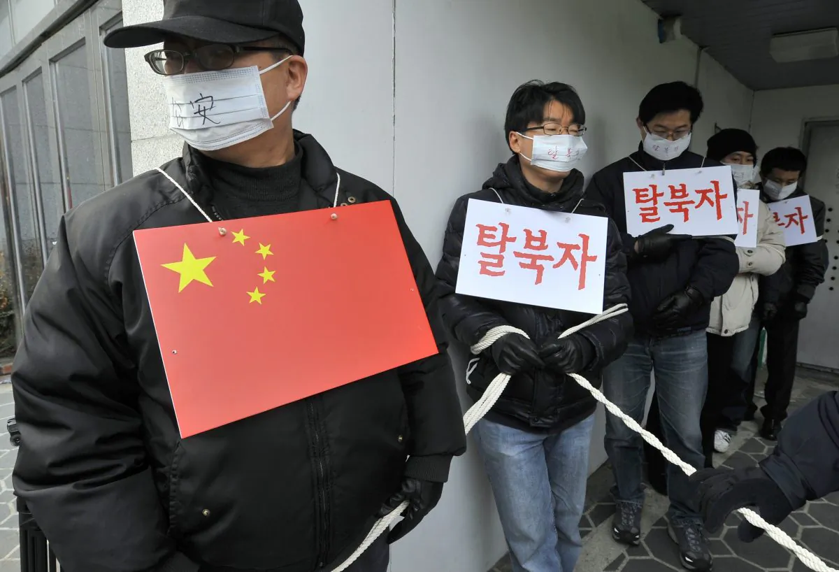 The photo shows rights activists performing the roles of Chinese police and North Korean refugees outside the Chinese Embassy in Seoul on Feb. 21, 2012 during a rally demanding that Beijing scrap plans to repatriate arrested refugees from North Korea. The Chinese regime has intensified its crackdown on North Koreans who attempt to escape the Kim regime through China. (JUNG YEON-JE/AFP/Getty Images)
