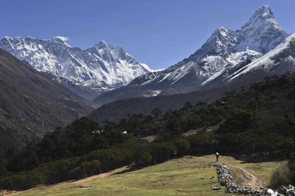 A Nepalese porter carries goods along a pathway in the Himalayas, with Mount Everest on the left, in the village of Tembuche in the Khumbu region of northeastern Nepal on April 20, 2015. (Roberto Schmidt/AFP/Getty Images)