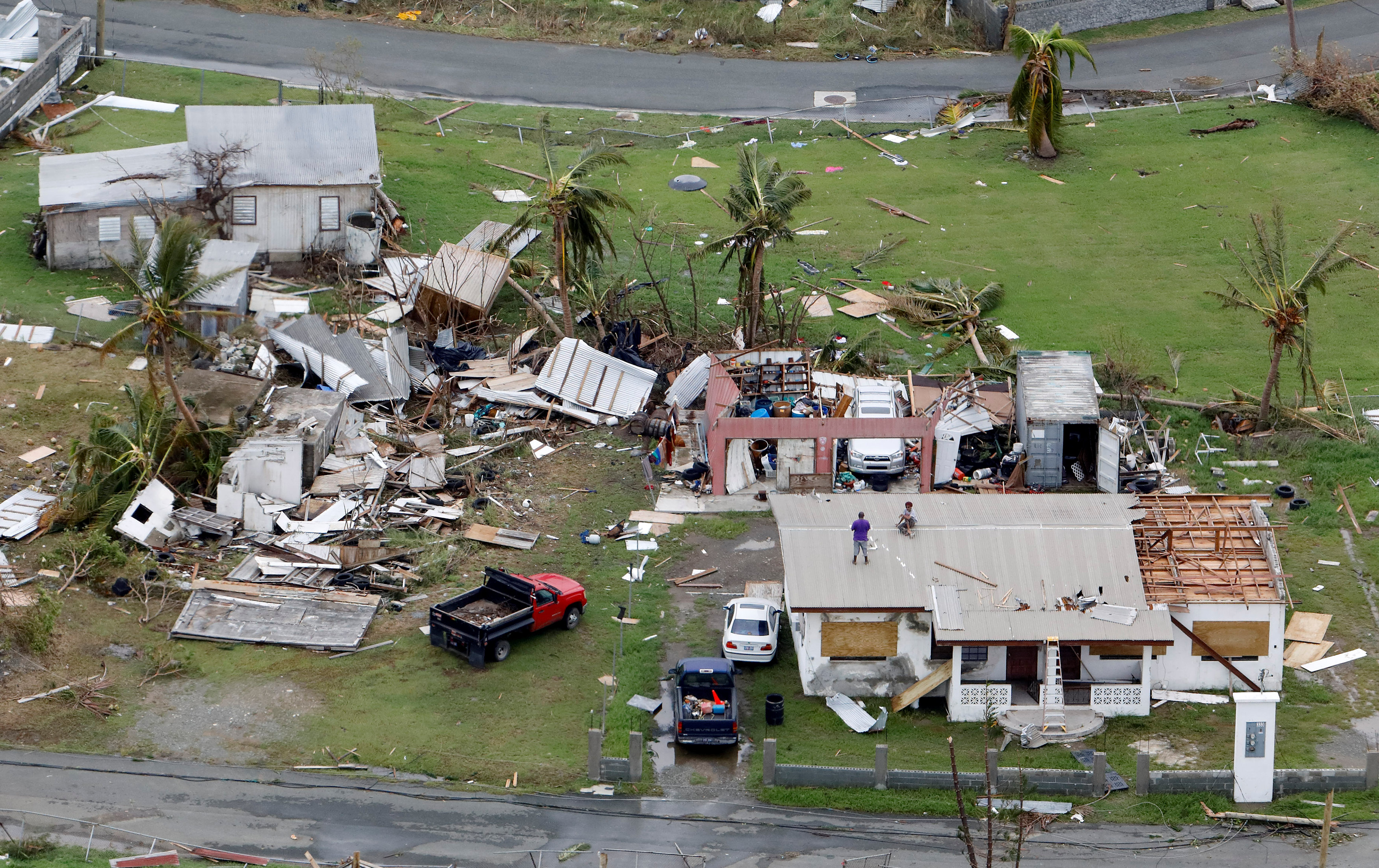Residents working on their roof in badly damaged neighborhood are seen from a Marine Corps MV-22 Osprey surveying the aftermath from Hurricane Maria in St. Croix, , U.S. Virgin Islands on Sept. 21, 2017. (REUTERS/Jonathan Drake)