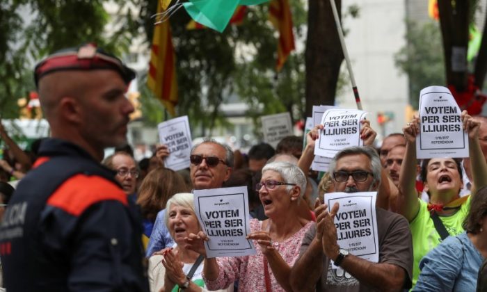 People shout slogans and hold up posters reading, "Vote to be free", referring to voting in the banned October 1st independence referendum, as protesters gather in support of Catalan officials that were arrested in raids on government offices, outside a courthouse in Barcelona, Spain on  Sept. 22, 2017. (REUTERS/Susana Vera)