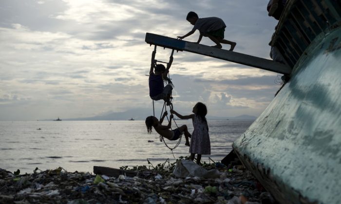 Filipino children play with a broken fishing boat in garbage filled Manila Bay. (Noel Celis/AFP/Getty Images)