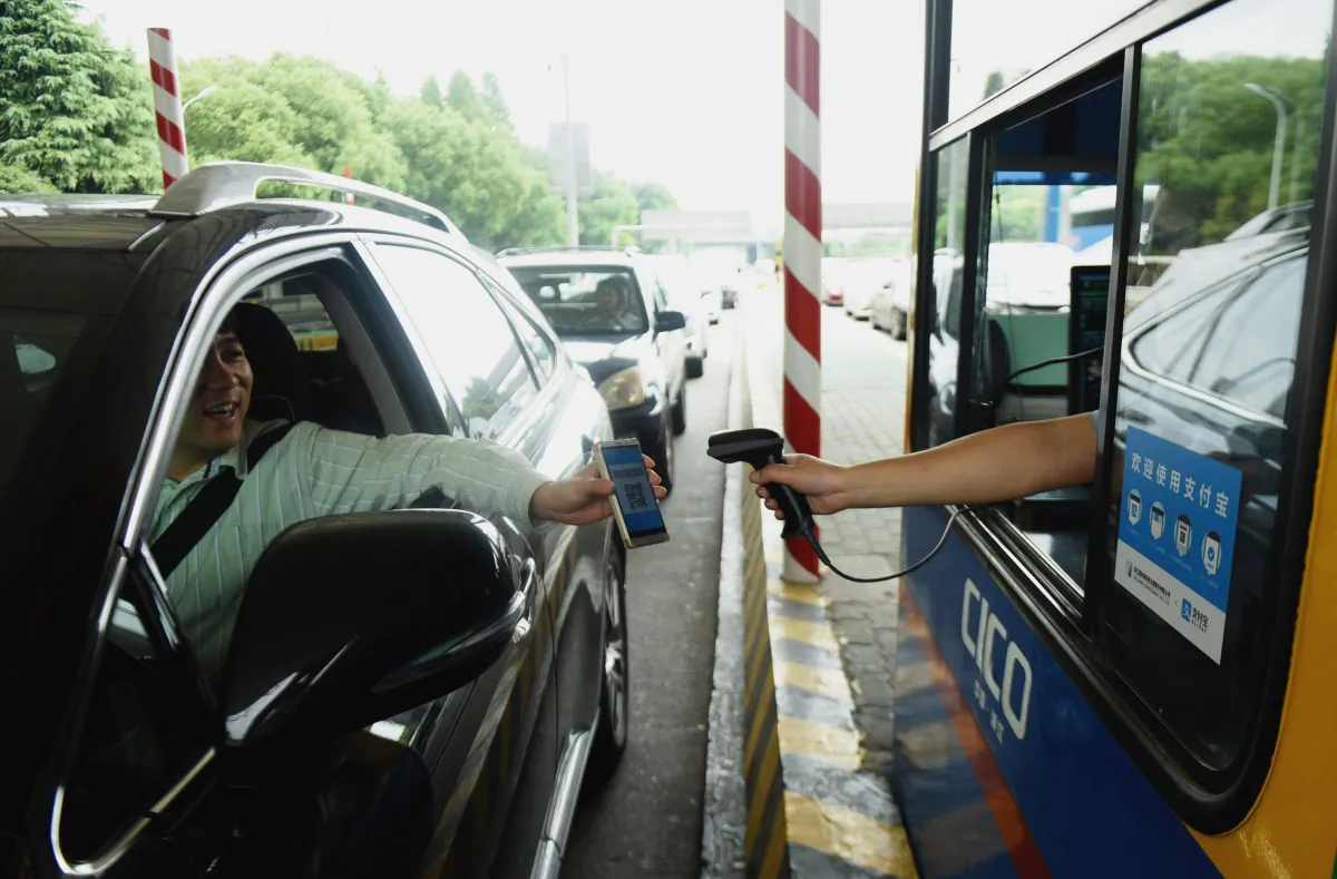 A driver uses his smartphone to pay the highway toll via Alipay, a mobile payment service, in Hangzhou city, Zhejiang province, on September 21, 2016. (STR/AFP/Getty Images)