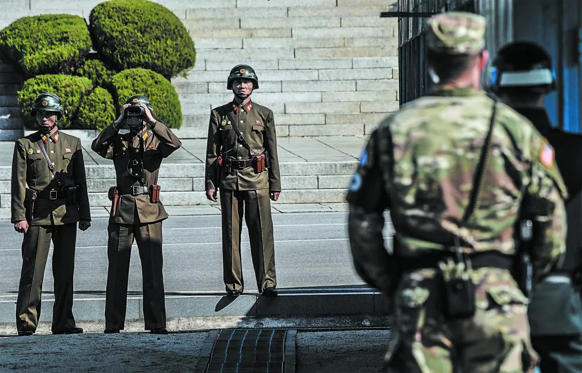 North Korean soldiers look toward the south while a U.S. solider (front) stands guard with a South Korean soldier in the truce village of Panmunjom in the Demilitarized Zone on the border between North and South Korea, on Oct. 27. (JUNG YEON-JE/AFP/GETTY IMAGES)