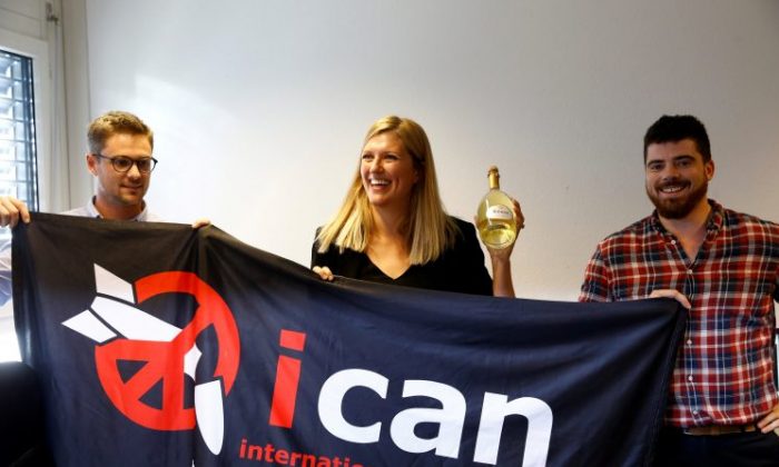 Beatrice Fihn, Executive Director of the International Campaign to Abolish Nuclear Weapons (ICAN) receives a bottle of champagne from her husband Will Fihm Ramsay (R) next to Daniel Hogsta, coordinator, while they celebrate after ICAN won the Nobel Peace Prize 2017, in Geneva, Switzerland on Oct. 6, 2017. (REUTERS/Denis Balibouse)