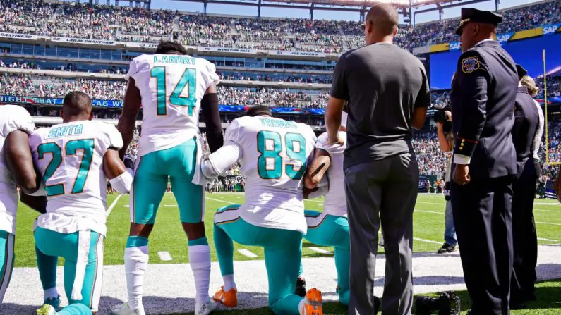 Maurice Smith #27 and Julius Thomas #89 kneel, while Jarvis Landry #14 of the Miami Dolphins stands during the National Anthem prior to an NFL game against the New York Jets at MetLife Stadium in East Rutherford, New Jersey on Sept. 24, 2017. (Steven Ryan/Getty Images)