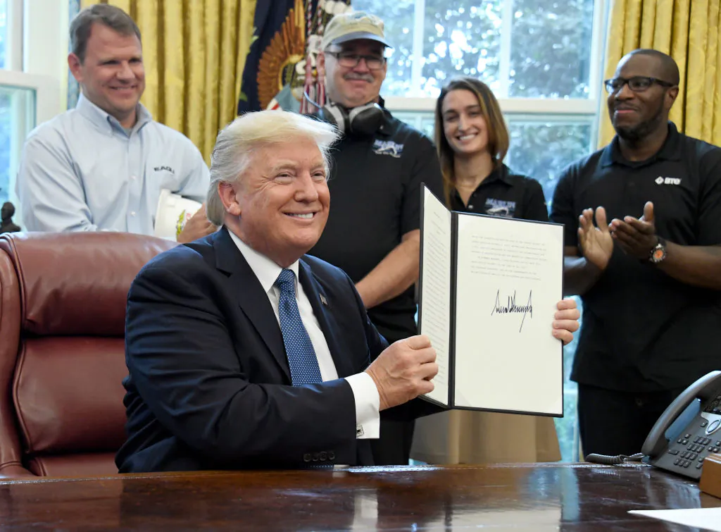 President Donald Trump displays a National Manufacturing Day Proclamation after signing it in the Oval Office of the White House in Washington, DC on Oct. 6, 2017. (Ron Sachs - Pool/Getty Images)