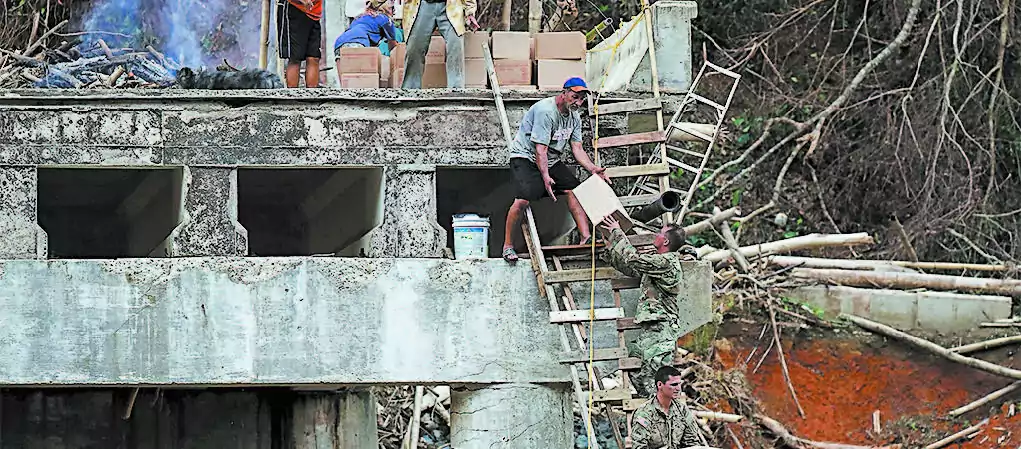 Members of the U.S. Army deliver boxes of food and water up a makeshift ladder to residents in Utuado, Puerto Rico, who were cut off after a bridge collapsed, on Oct. 5. (JOE RAEDLE/GETTY IMAGES)