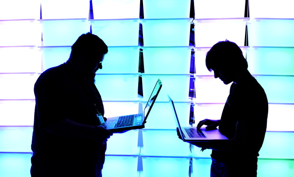 Participant hold their laptops in front of an illuminated wall at the annual Chaos Computer Club (CCC) computer hackers' congress. (Photo by Patrick Lux/Getty Images)