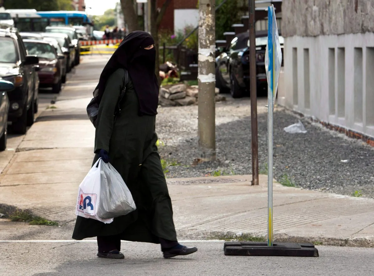 A woman wearing a niqab as she walks in a street in Montreal. Quebec lawmakers have passed a religious neutrality bill that obliges citizens to uncover their faces while giving and receiving state services. (The Canadian Press/Ryan Remiorz)