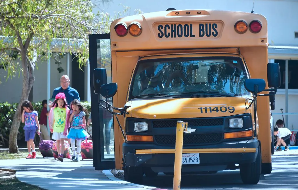 Children walk past a School Bus in Monterey Park, California on April 28, 2017. (Frederic J. Brown/AFP/Getty Images)