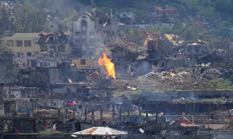 Flame rises as damaged buildings are seen after government troops cleared the area from pro-ISIS terrorists groups inside a war-torn area in Marawi city, southern Philippines Oct. 23, 2017. (Reuters/Romeo Ranoco)