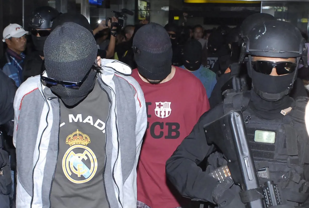 Elite Indonesian anti-terror police from Densus 88 escort four Turks arrested on arrival at Jakarta airport on Sept. 14, 2014. The four Turkish nationals were arrested in Sulawesi island and are suspected to be linked to the jihadist Islamic State group, police spokesman said. (BIMA SAKTI/AFP/Getty Images)