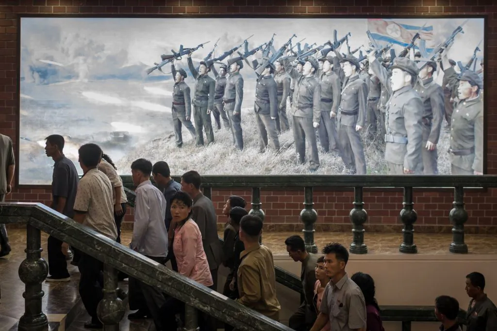 People walk up the stairs before a propaganda poster showing Korean People's Army (KPA) soldiers at a museum in Sinchon, south of Pyongyang, North Korea, on July 29, 2017. North Korea said on July 30 its latest ICBM test was a "warning" targeting the United States for its efforts to slap new sanctions on Pyongyang and threatened a counter-strike if provoked militarily by Washington. (Ed Jones/AFP/Getty Images)